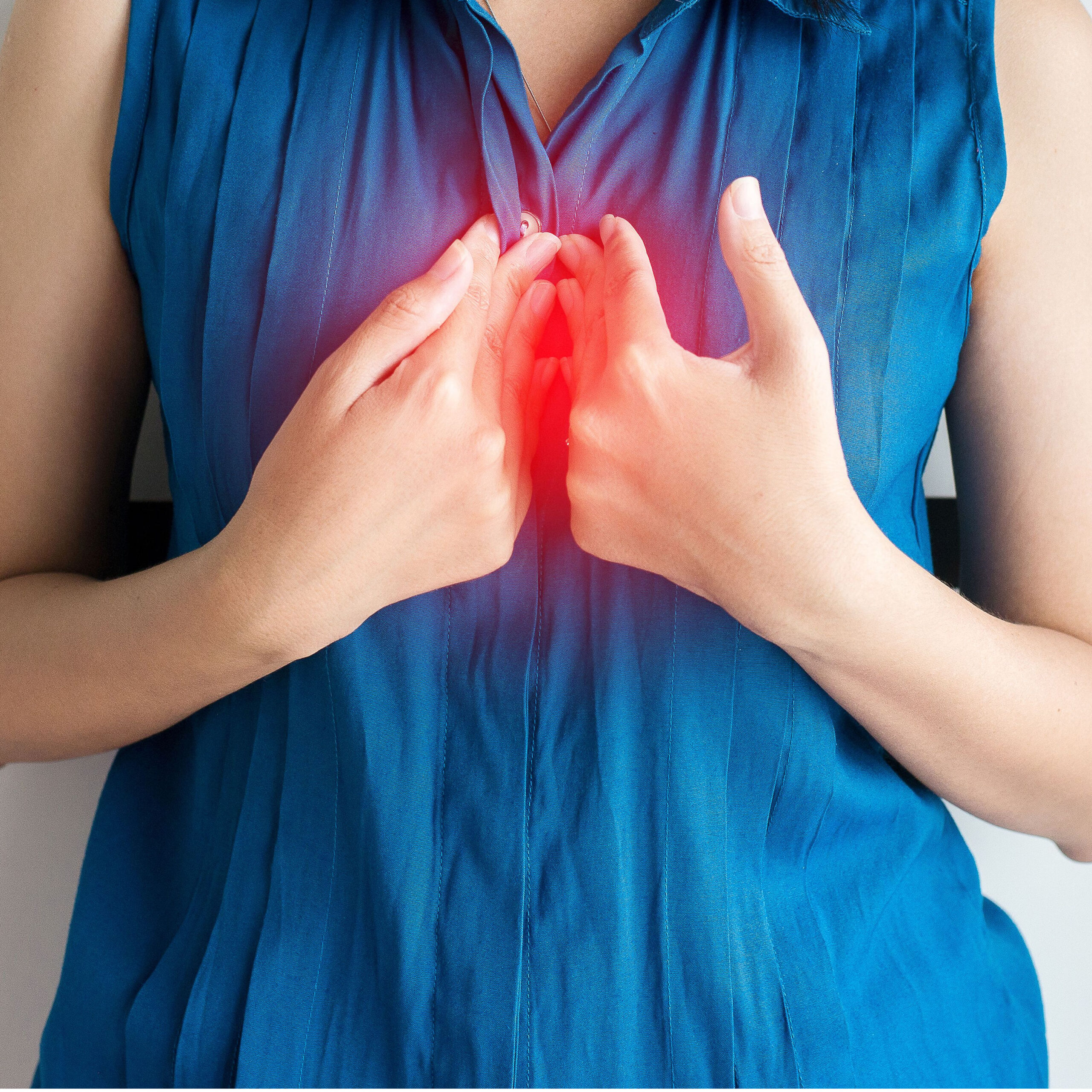 woman pressing hands to chest in pain from heartburn