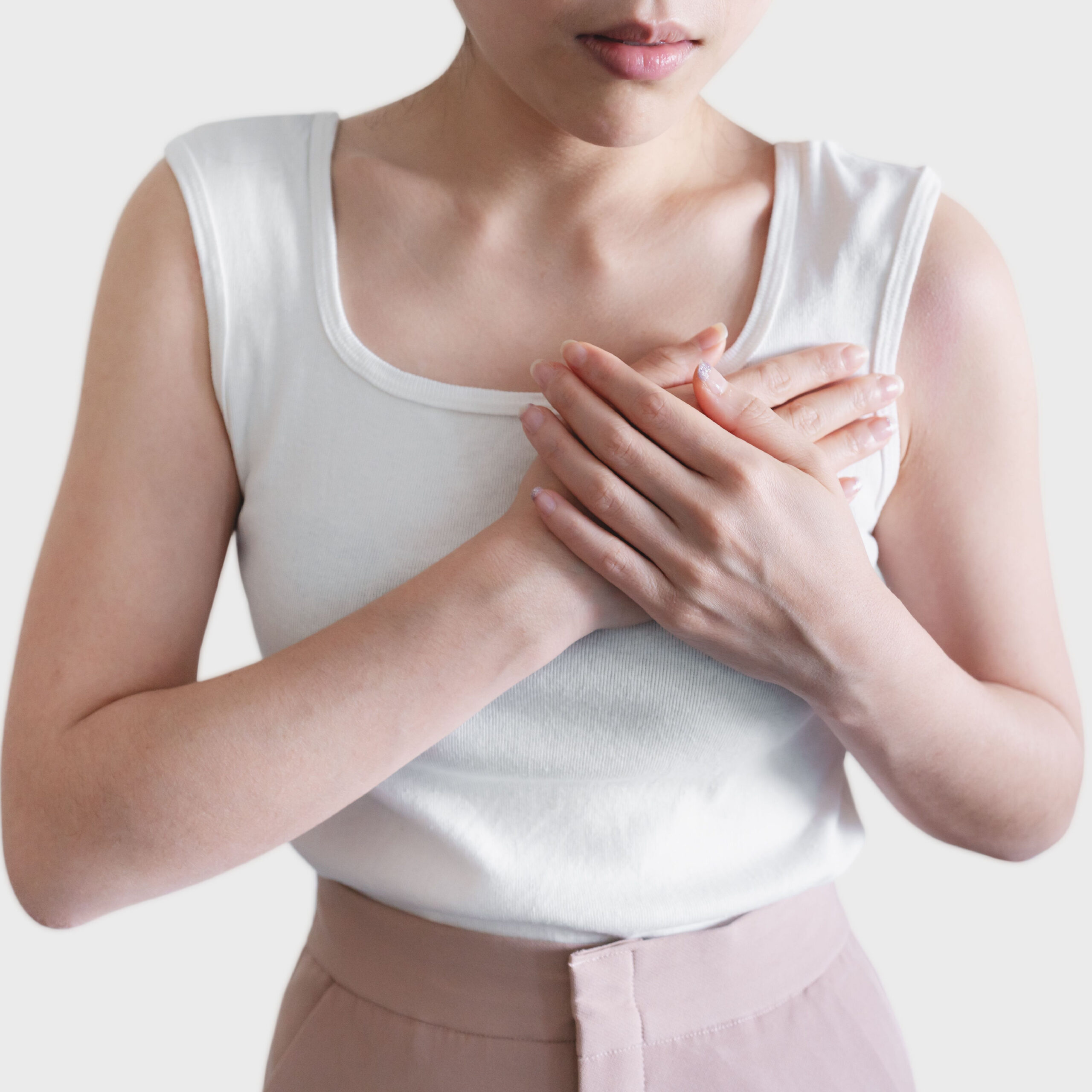 woman in white tank top holding hands over heart