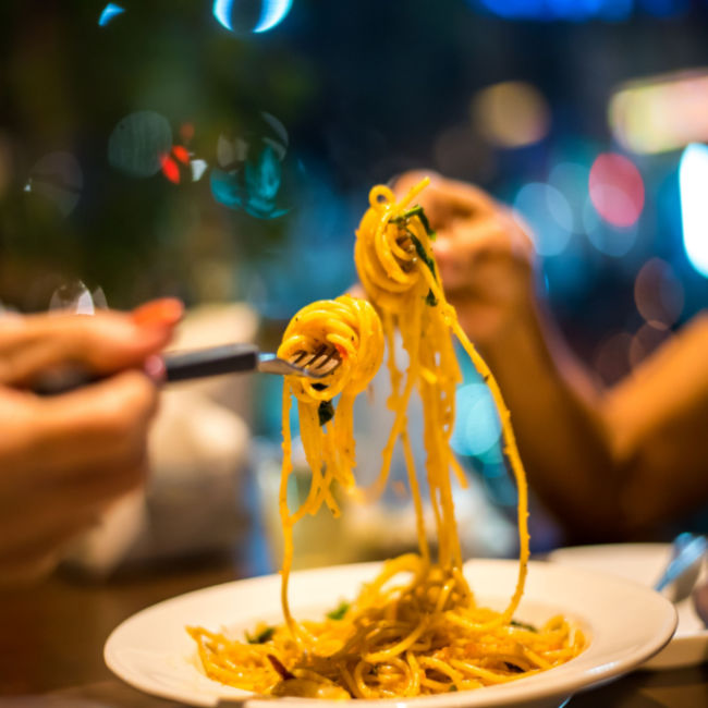 couple sharing plate of pasta at restaurant