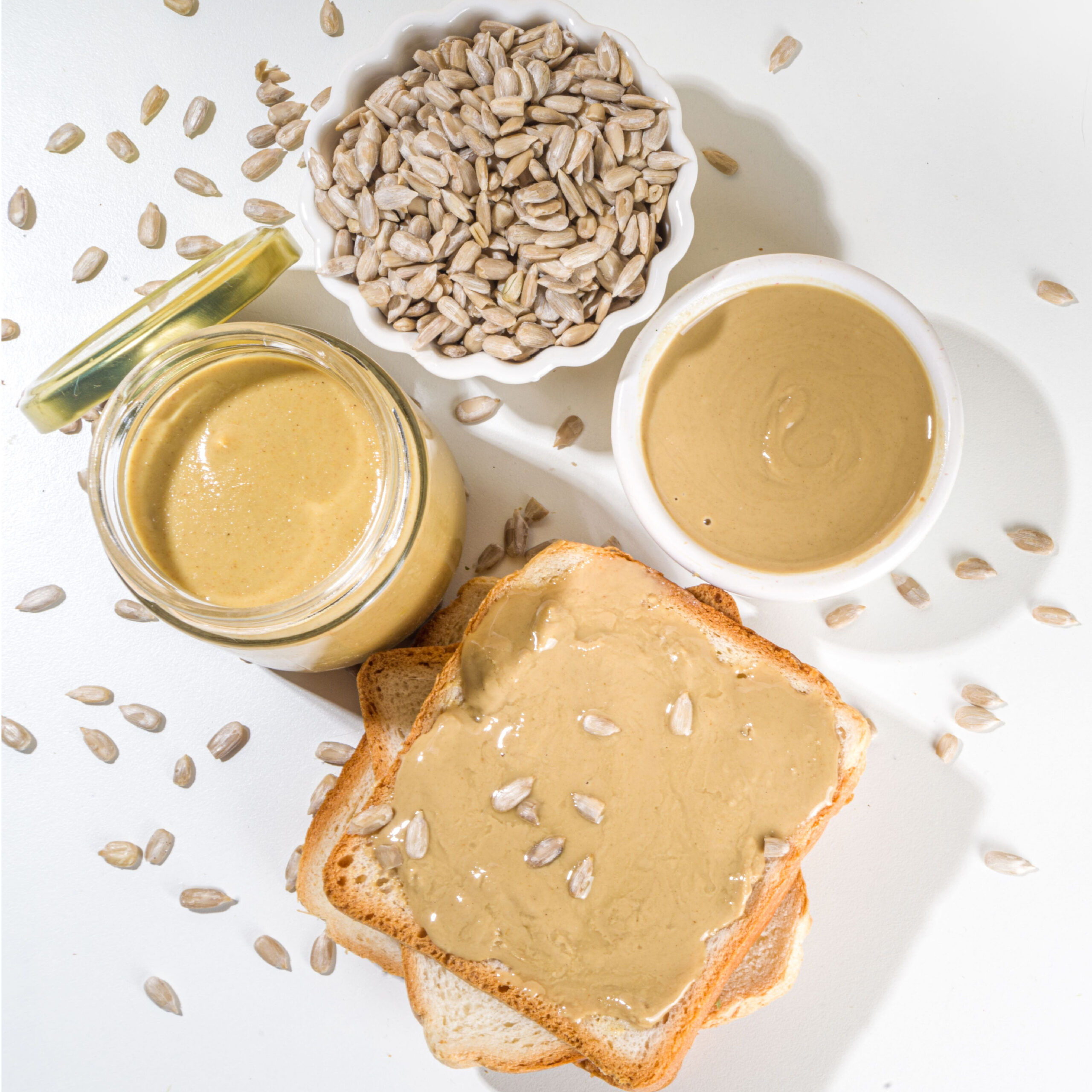 sunflower seed butter on toast beside jar of the butter and bowl of sunflower seeds
