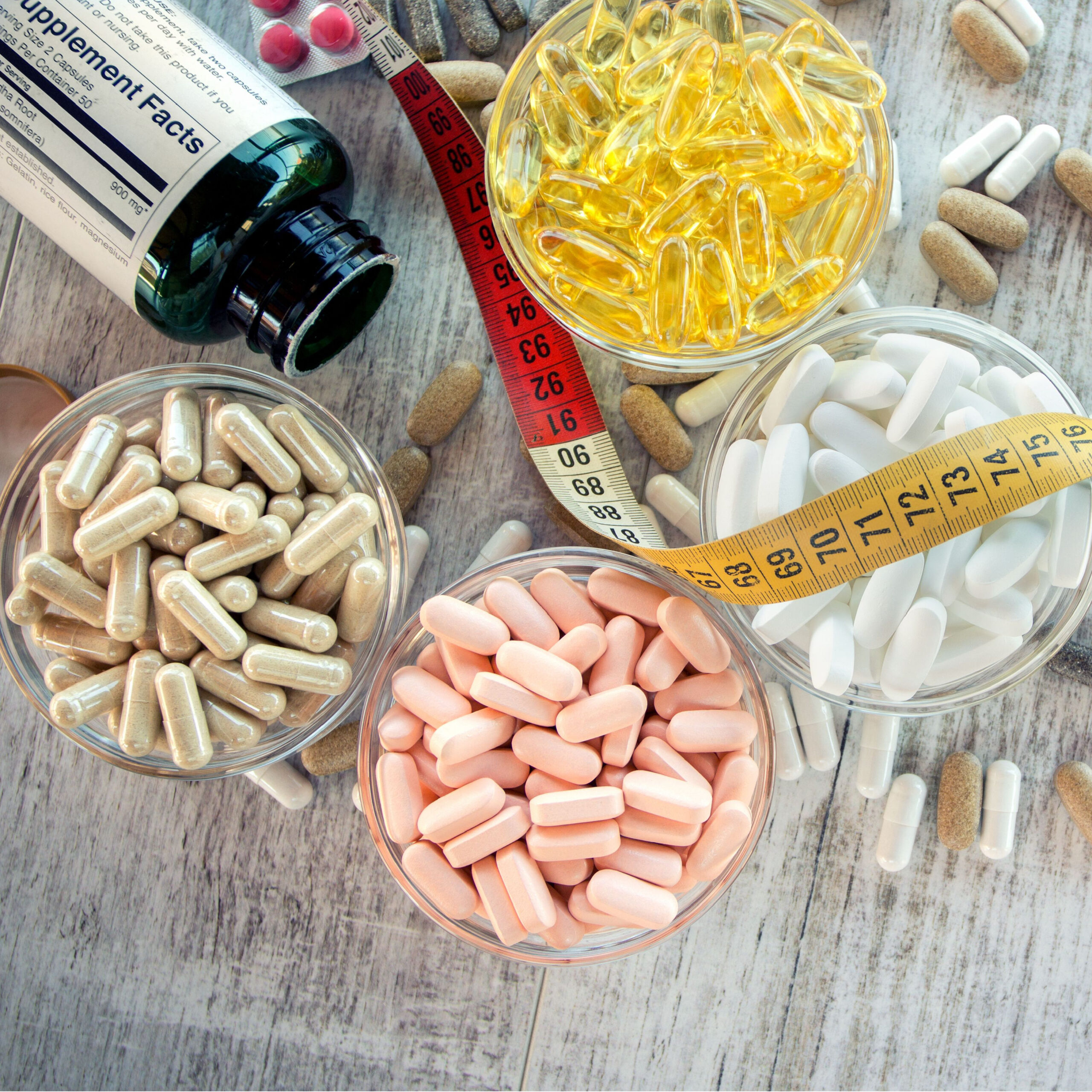 various weight loss supplements on table with measuring tape