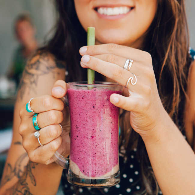 woman drinking a pink smoothie