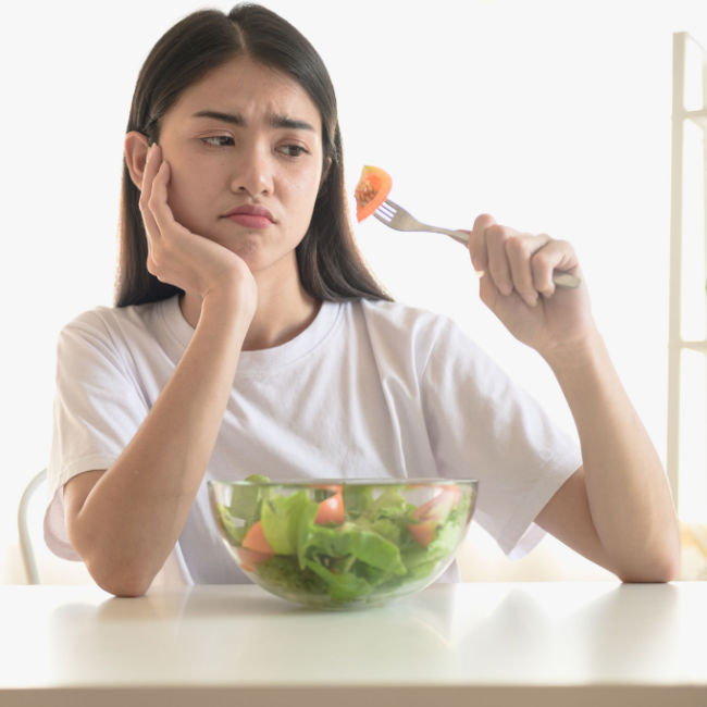 woman looking unhappy eating boring salad