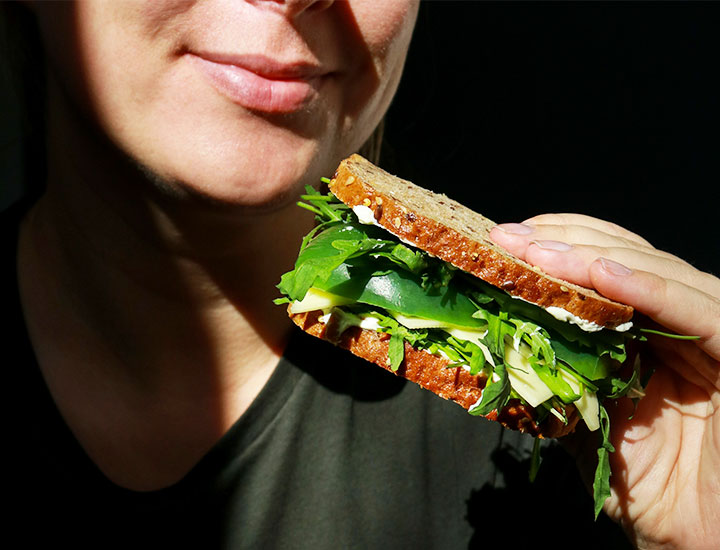 Woman eating a sandwich on whole wheat bread