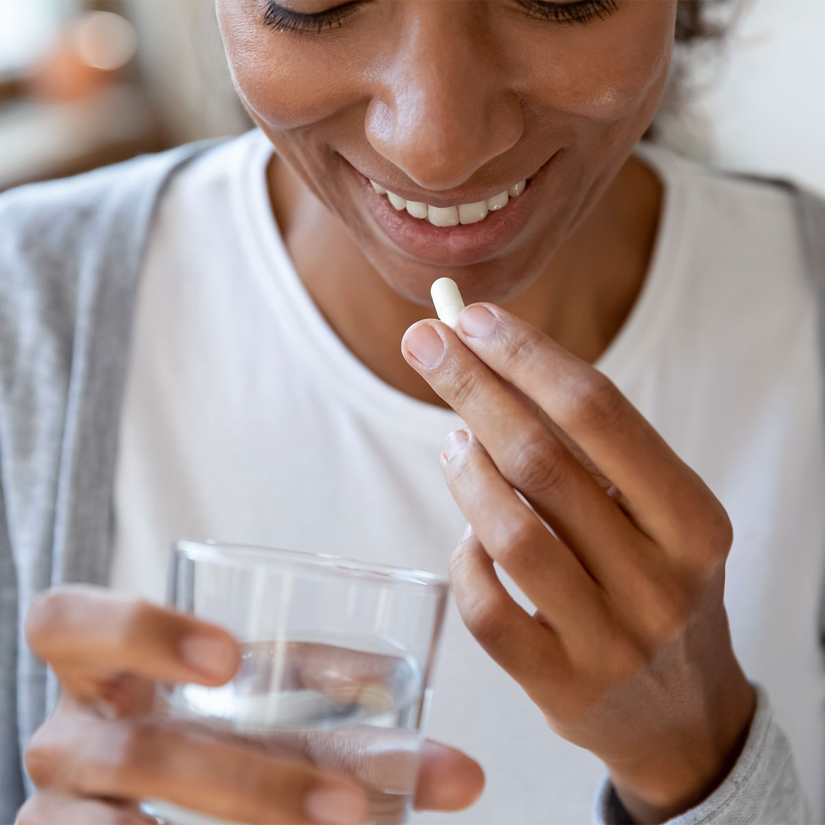 woman taking supplement with glass of water