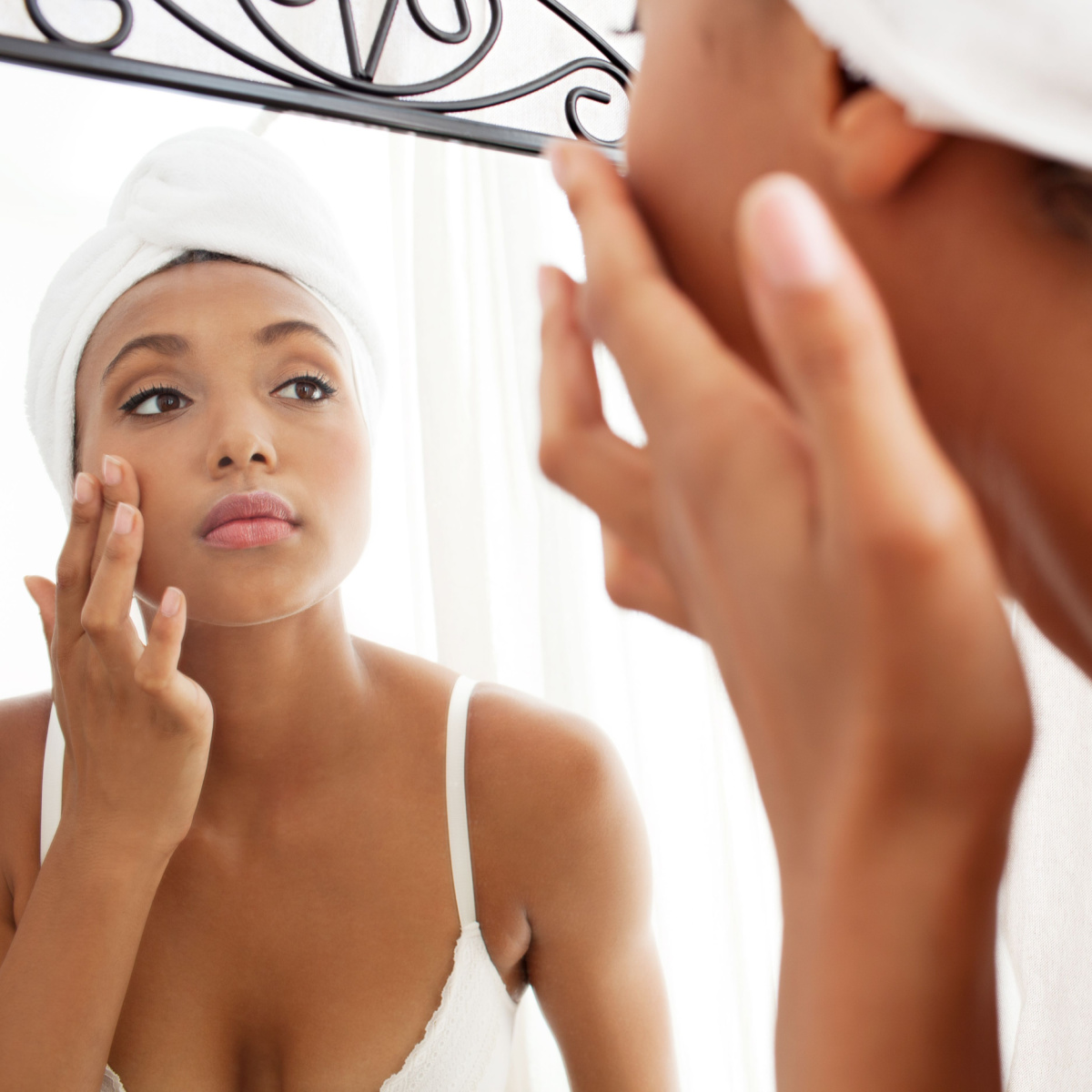 woman touching her face mirror white turban towel reflection clear skin white tank top