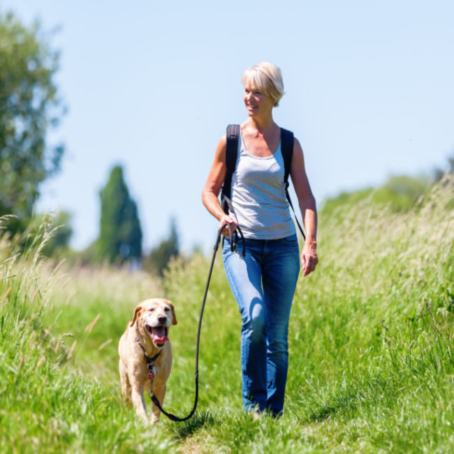 woman walking through field with dog