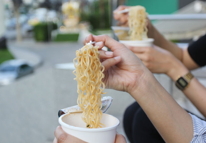 Person eating instant ramen noodle