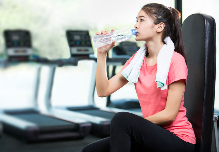 Woman drinking water after being on a treadmill