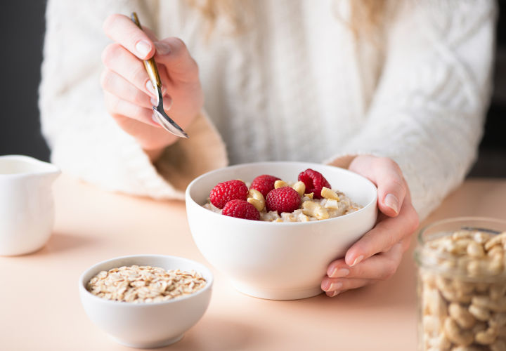 Woman eating oats with raspberries