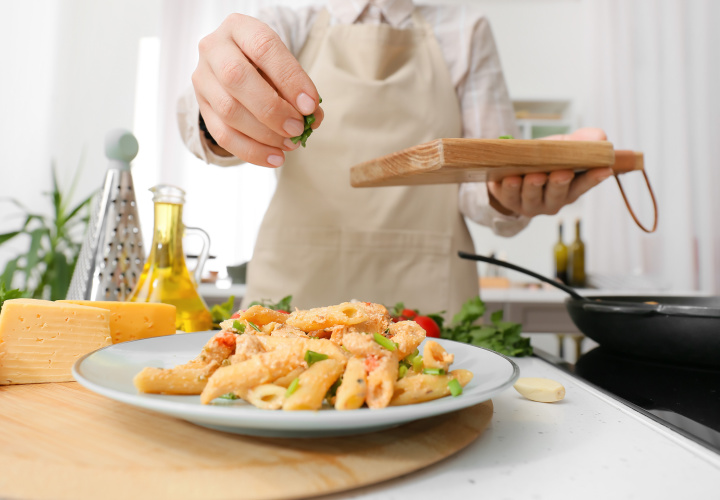 Woman adding cheese to pasta