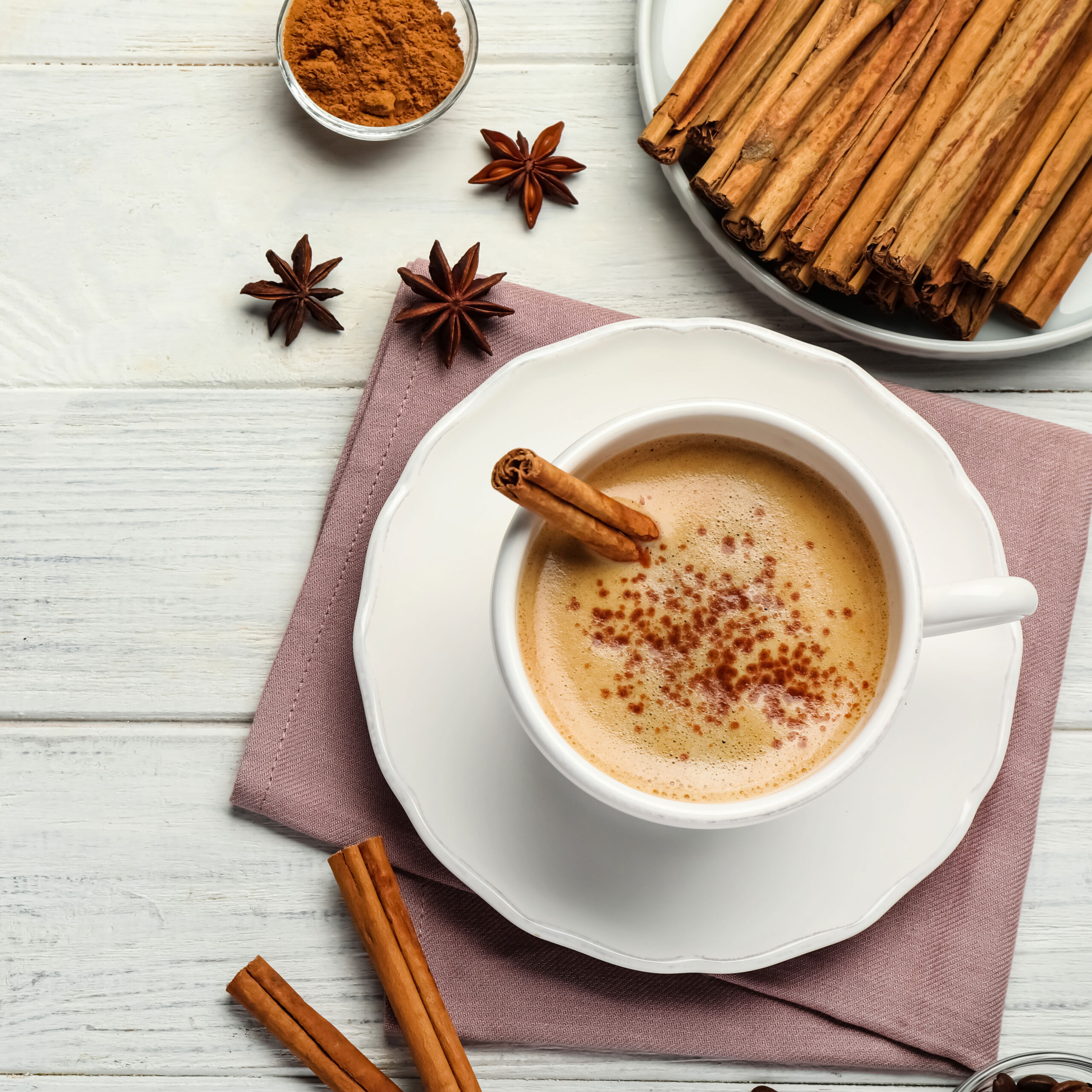 latte dusted with cinnamon beside plate of cinnamon sticks