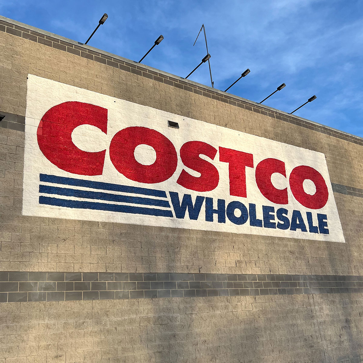 costco storefront red and blue sign blue sky shadows bricks building