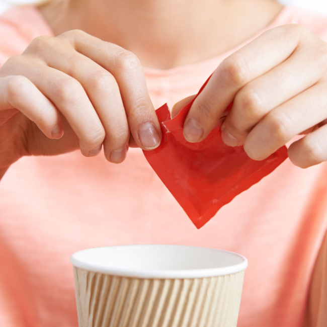 woman adding sweetener to coffee