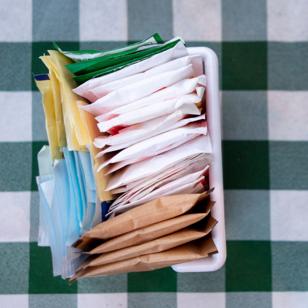 artificial sweeter packets in container on table