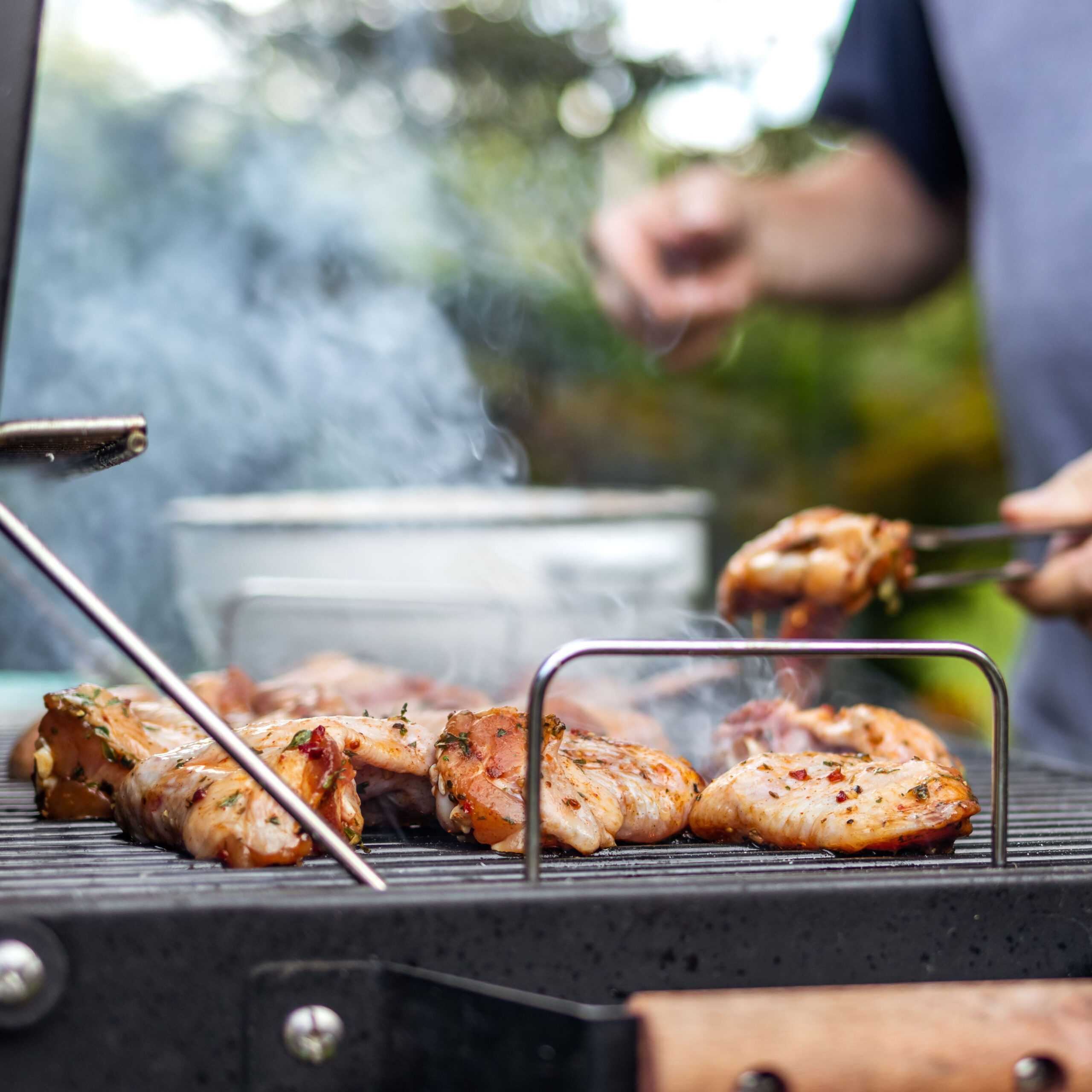 person flipping chicken on grill outdoors