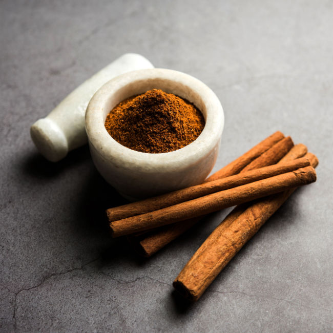 small bowl of cinnamon beside cinnamon sticks