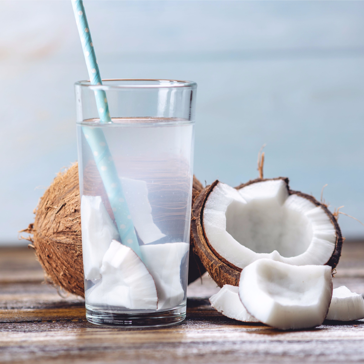 coconut water isolated clear glass blue straw sliced coconuts wooden table