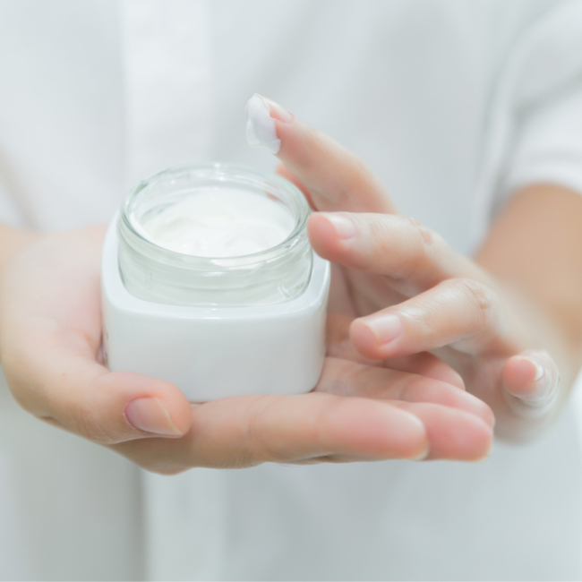 woman holding white cosmetic cream in hands