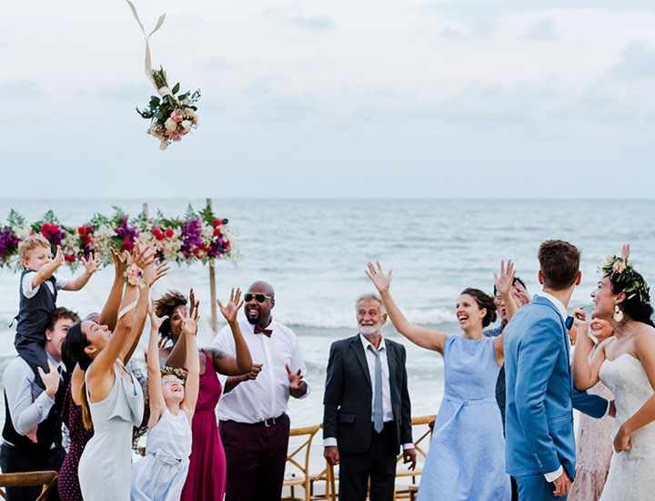 Bride tossing bouquet on the beach