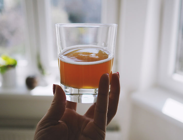 Hand holding a glass of kombucha