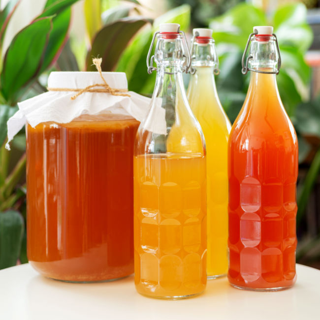 jar of kombucha besides glasses of kombucha