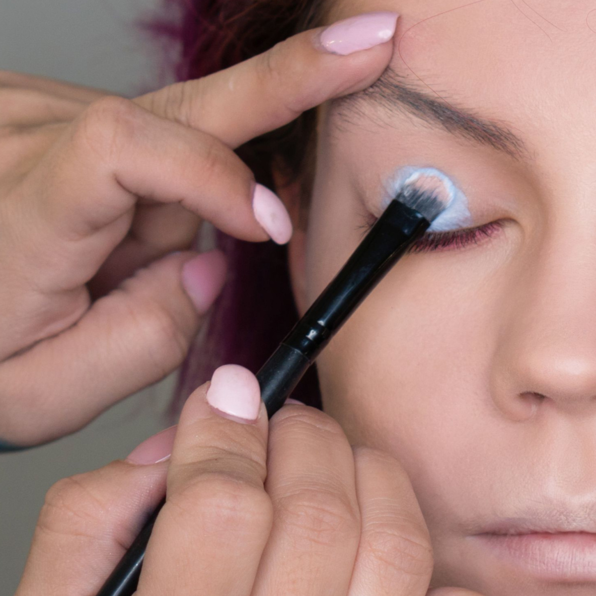 makeup artist applying primer to client eyelid with brush