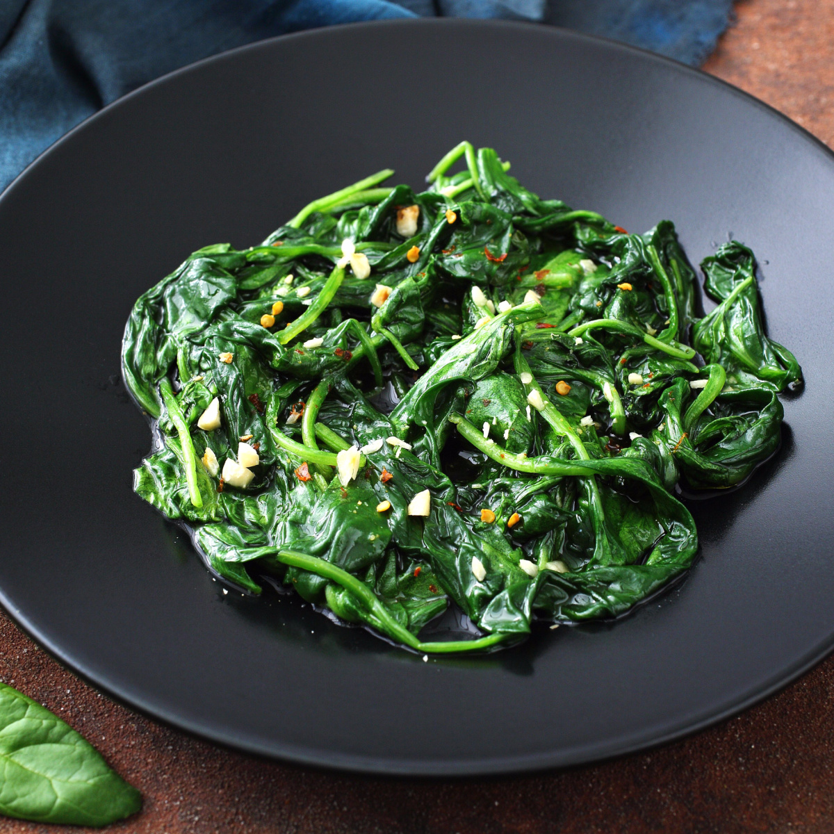 bowl of cooked dark green leafy spinach on black tupperware