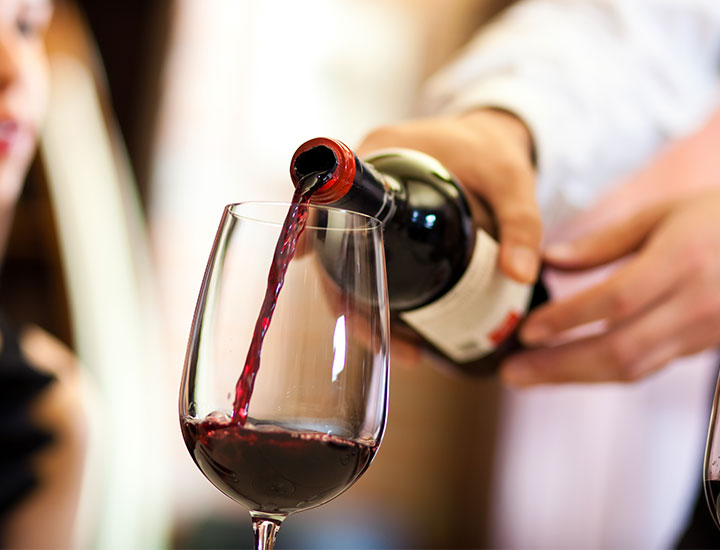 Waiter pouring a glass of red wine