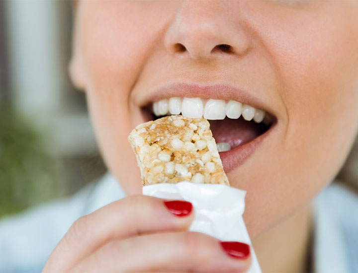 Woman biting into granola bar