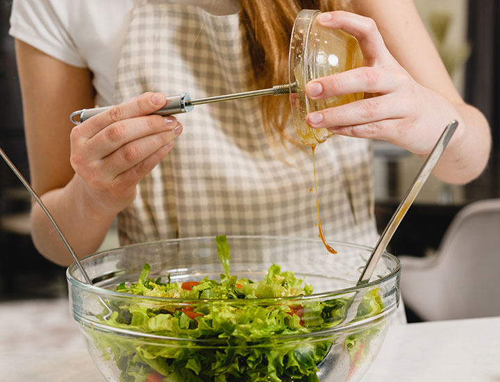 Woman pouring dressing on a salad