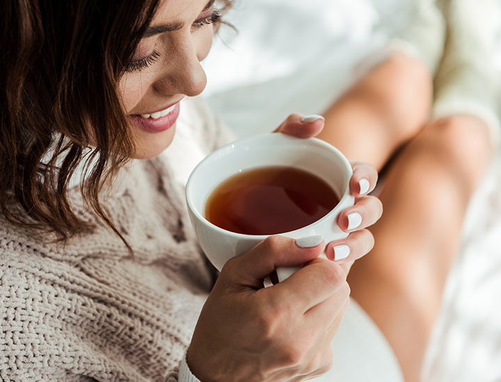 Woman sipping on tea in bed