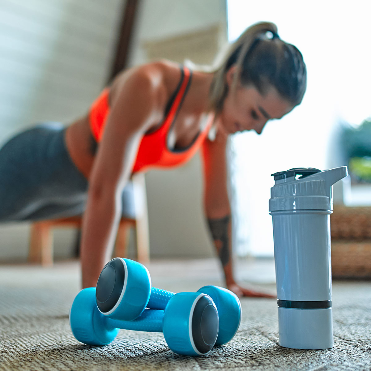 woman doing plank with hand weights in foreground