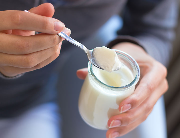 Woman holding yogurt and spoon