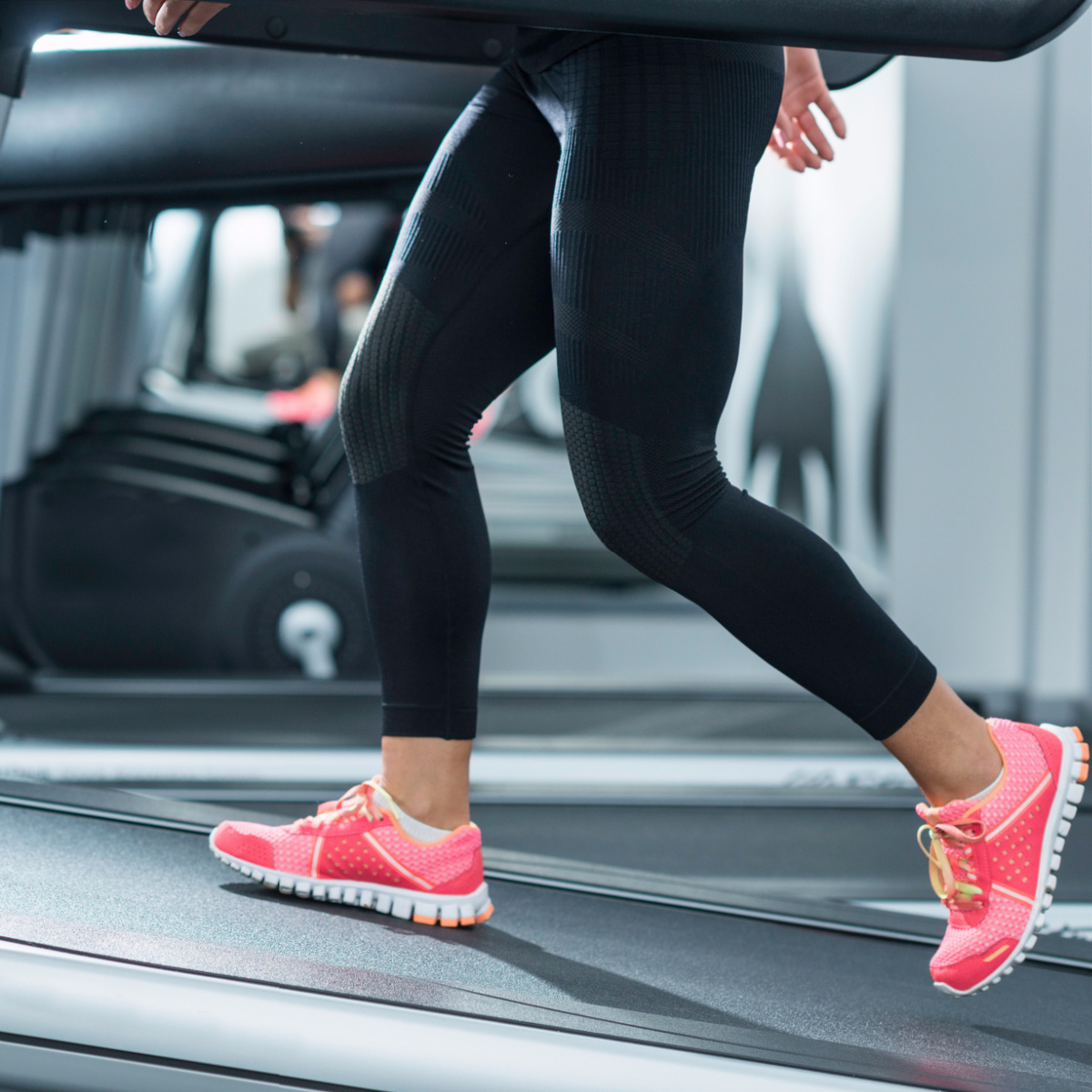 woman walking incline gym black leggings pink sneakers