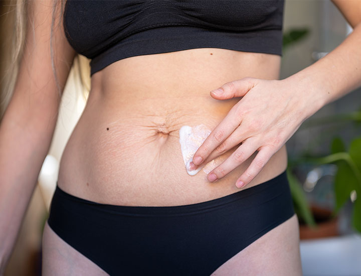 Woman applying toning cream to stomach