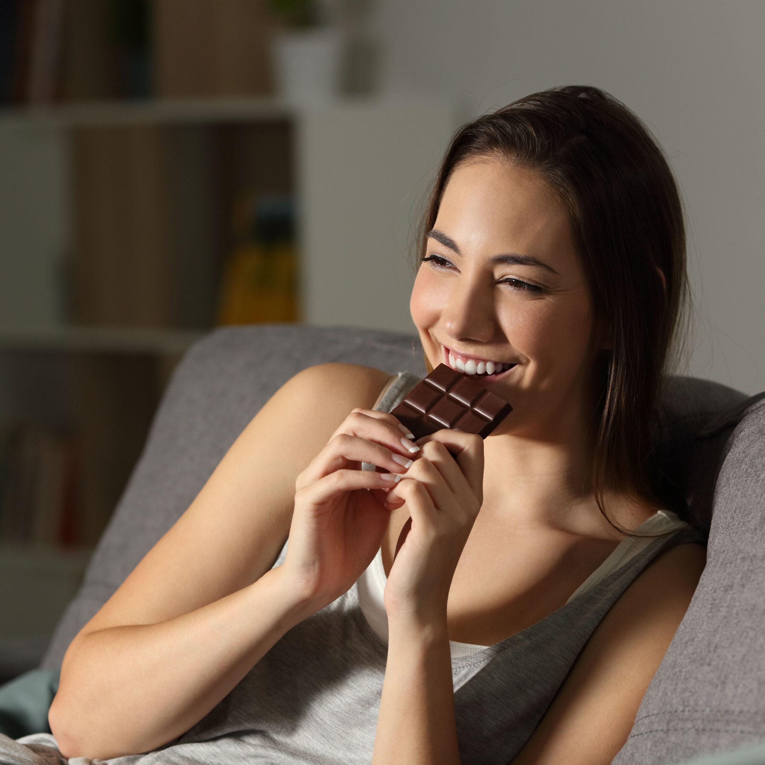 woman biting into dark chocolate bar