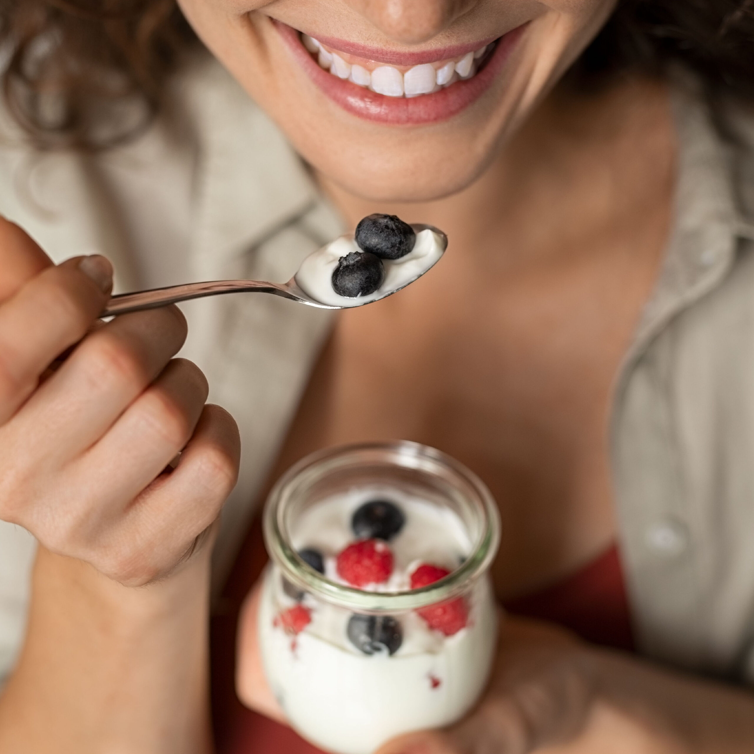 woman eating yogurt with berries and smiling