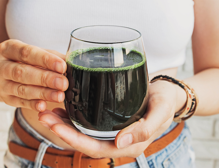 Woman holding a glass of green juice