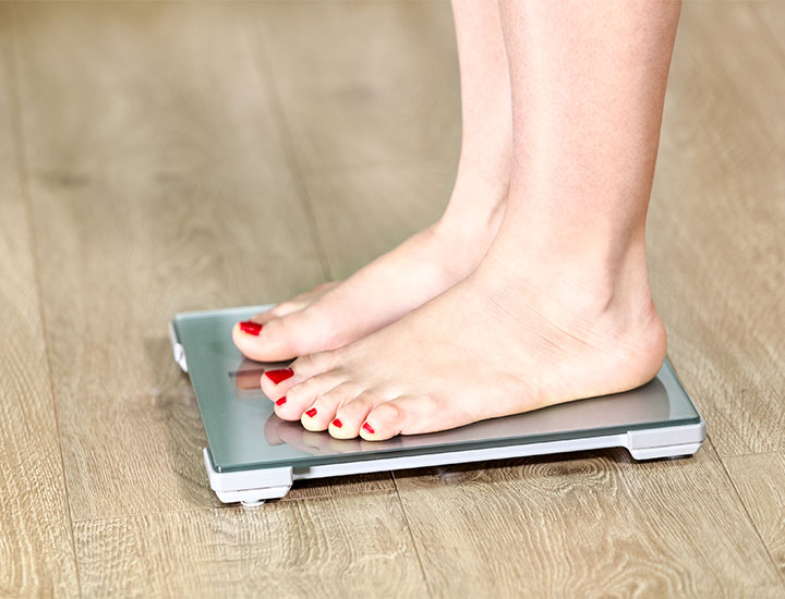 Woman with red pedicure stands on a scale