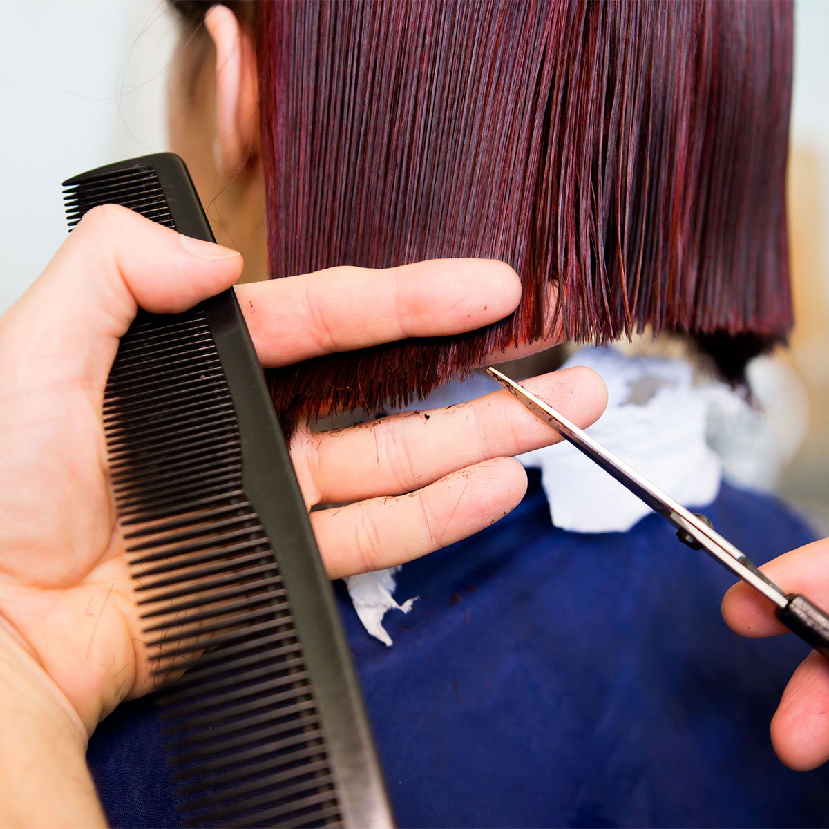 woman red hair getting hair cut salon trim scissors black comb