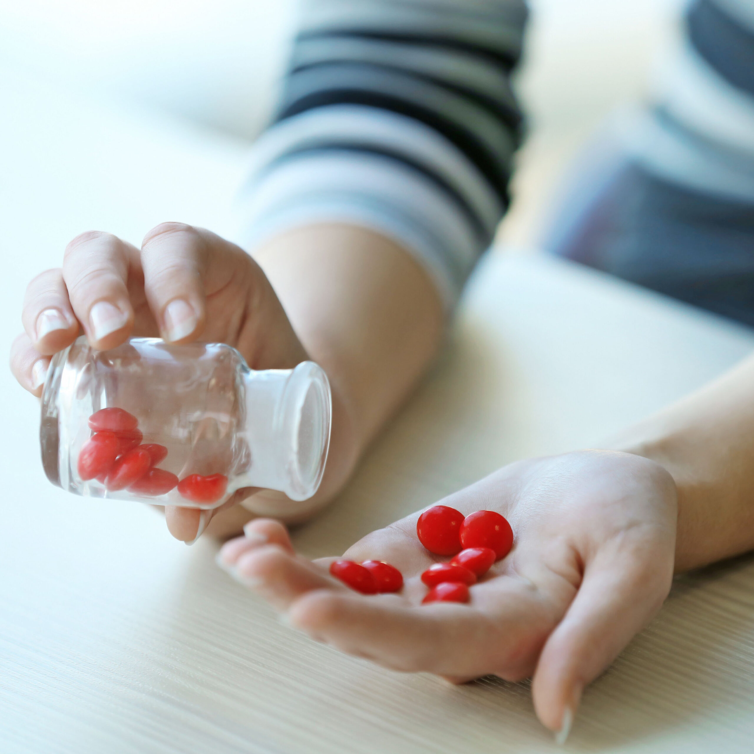 woman pouring red supplements into hand