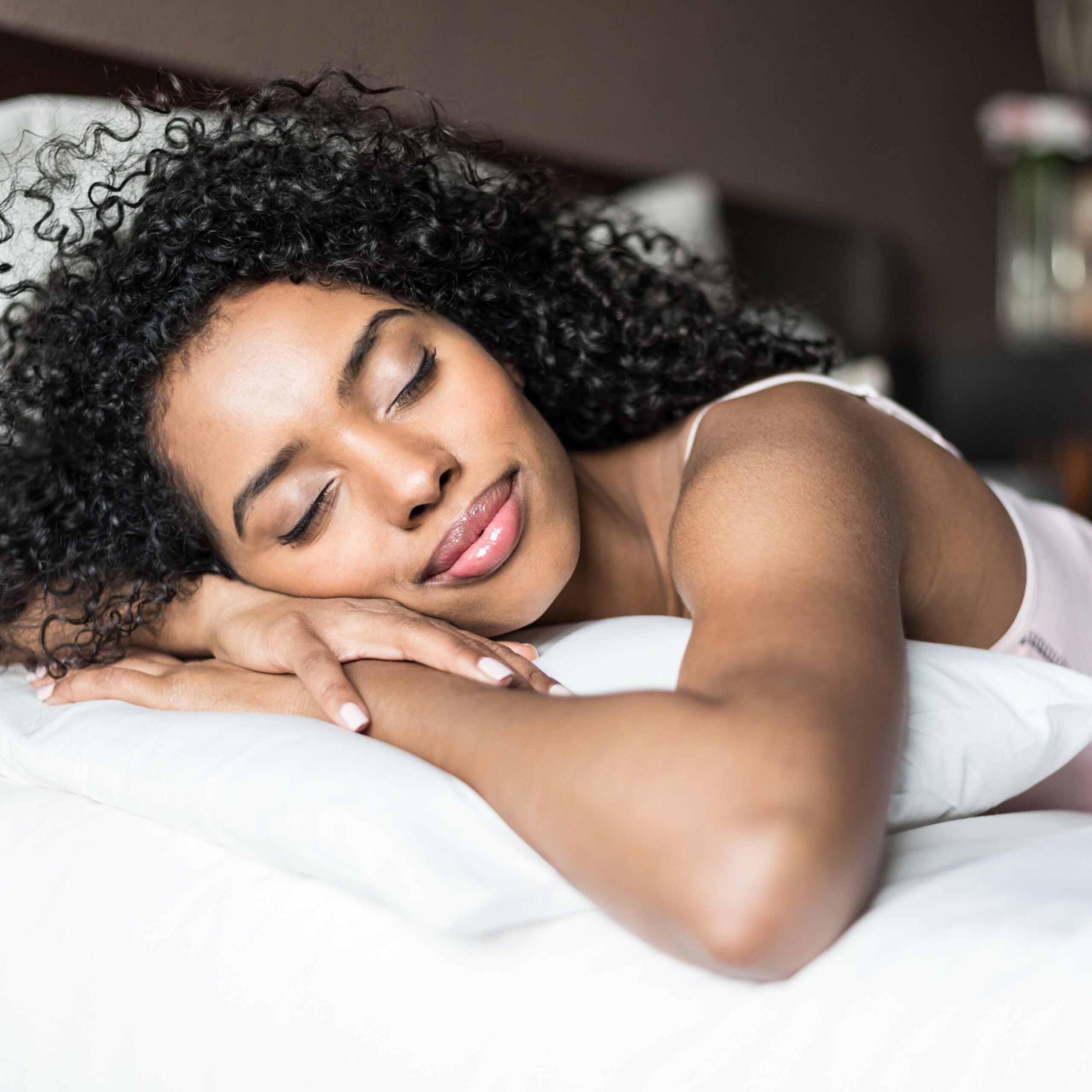 woman sleeping on pillowcase hair down smiling white sheets