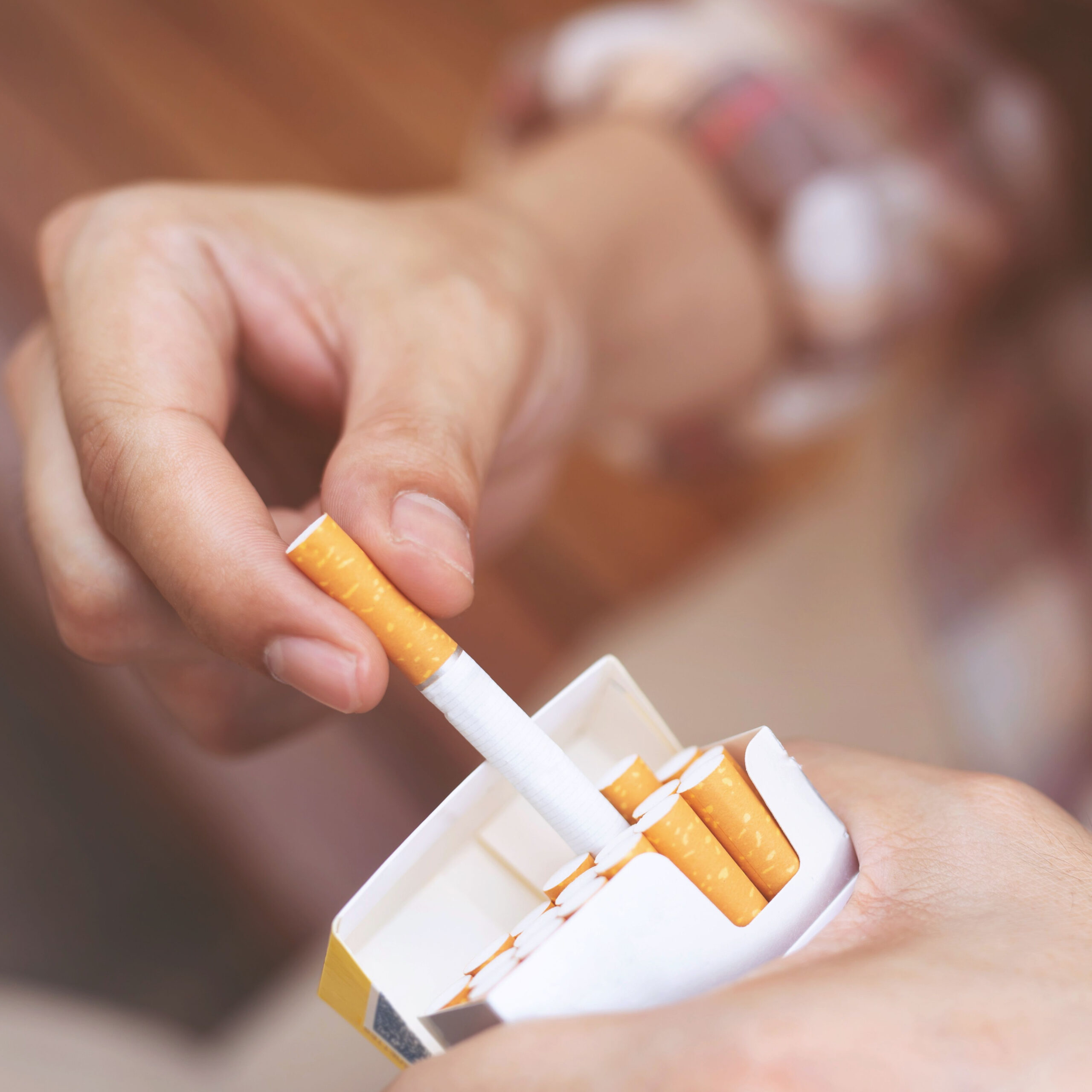 person pulling cigarette out of pack