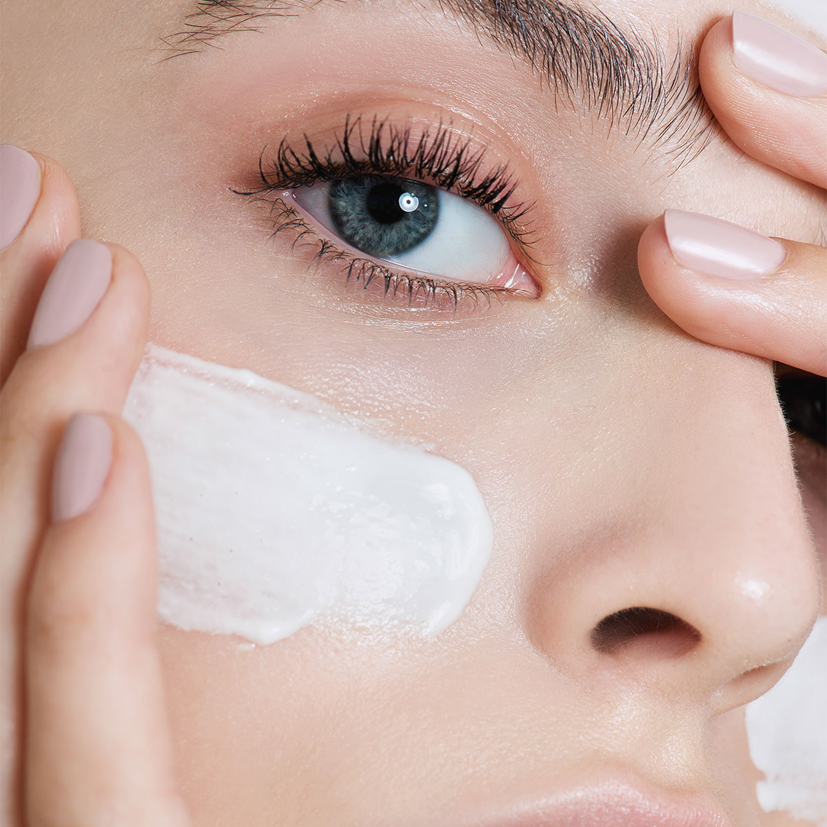 closeup woman applying white slab of sunscreen on cheek