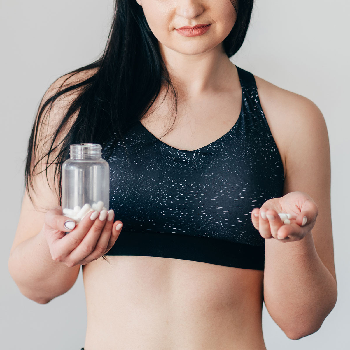 woman holding supplements long healthy brunette hair