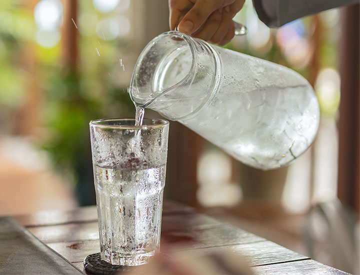 hand pouring ice water from a pitcher