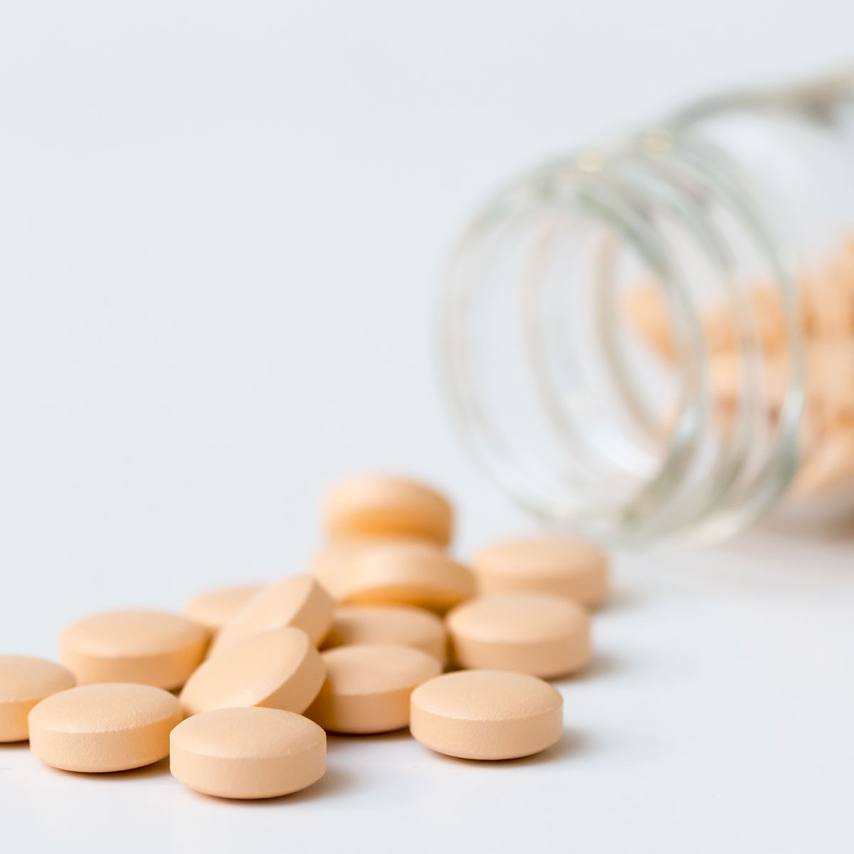 orange vitamin supplements spilled onto white surface isolated