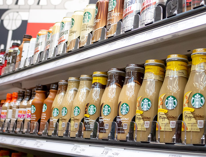 processed bottled starbucks coffees lined up in a row grocery store shelf