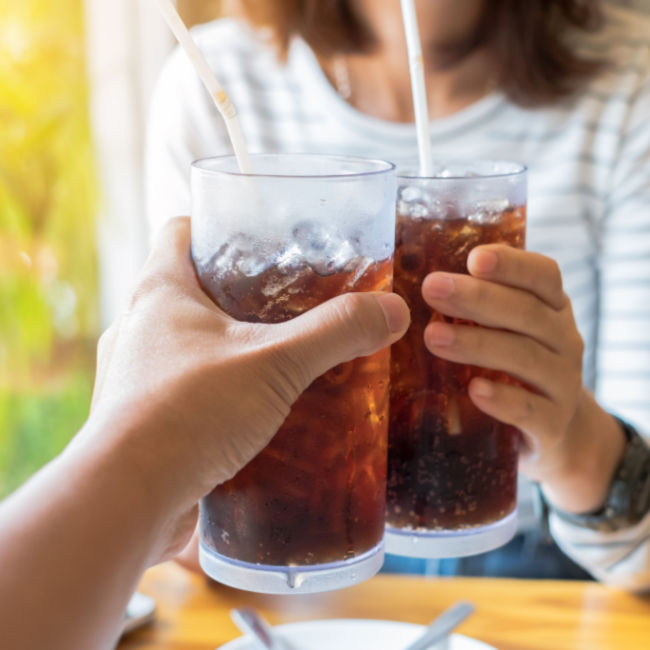 people cheersing glasses of soda with straws